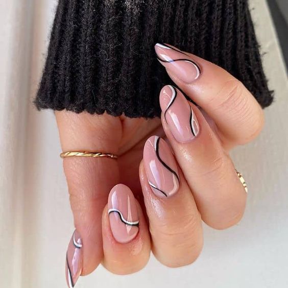 Vernis à ongles nude au fini brillant avec des tourbillons noirs et blancs sur des ongles ronds moyens