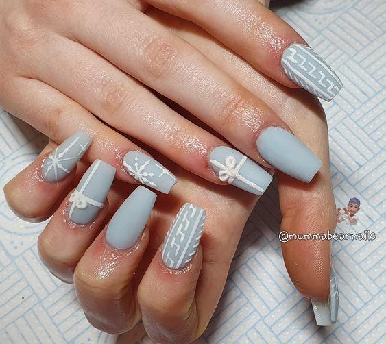 flocons de neige, cadeaux et pull en tricot sur ongles bleu clair