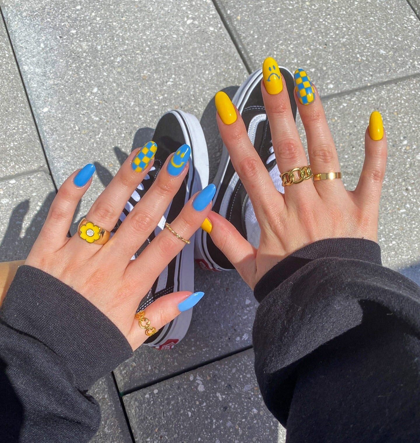 Couleur d’ongle bleue et jaune vibrante avec des visages souriants et des arts d’ongles abstraits sur de longs ongles ronds