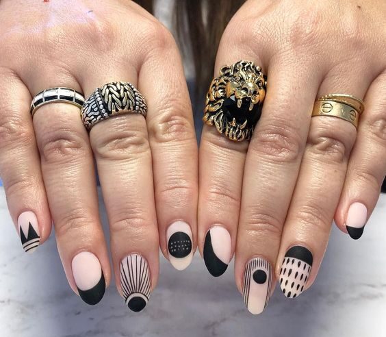 Vernis à ongles nude mat avec des motifs d’ongles abstraits noirs sur des ongles ronds moyens