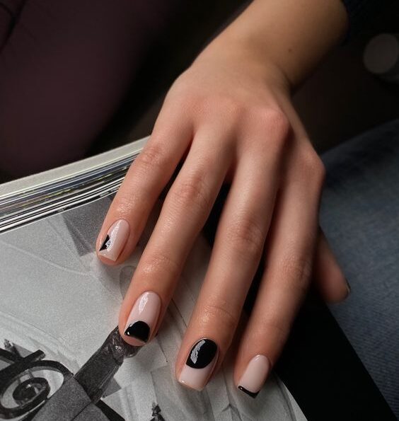 Couleur d’ongle nude pâle avec des motifs abstraits noirs sur des ongles carrés courts