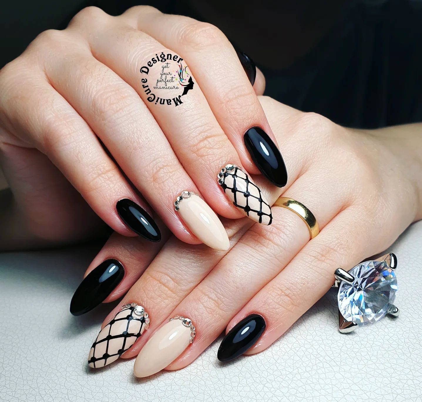 Couleurs d’ongles noires et nude avec des motifs géométriques élégants sur de longs ongles en amande