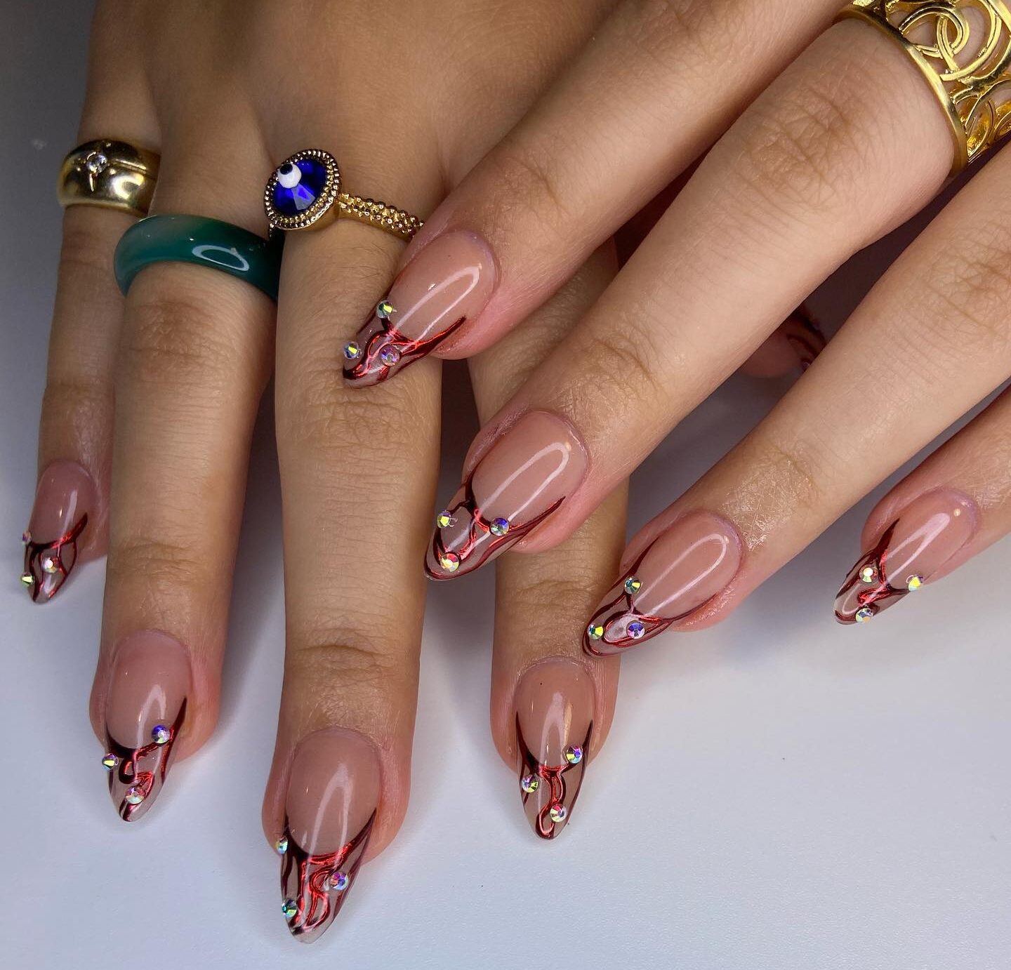 Chrome rouge abstrait pointes françaises avec pierres sur ongles en amande moyenne