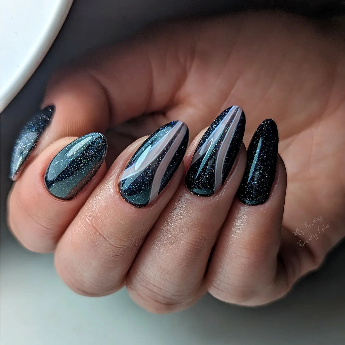 Vernis noir avec paillettes sur les ongles en amande