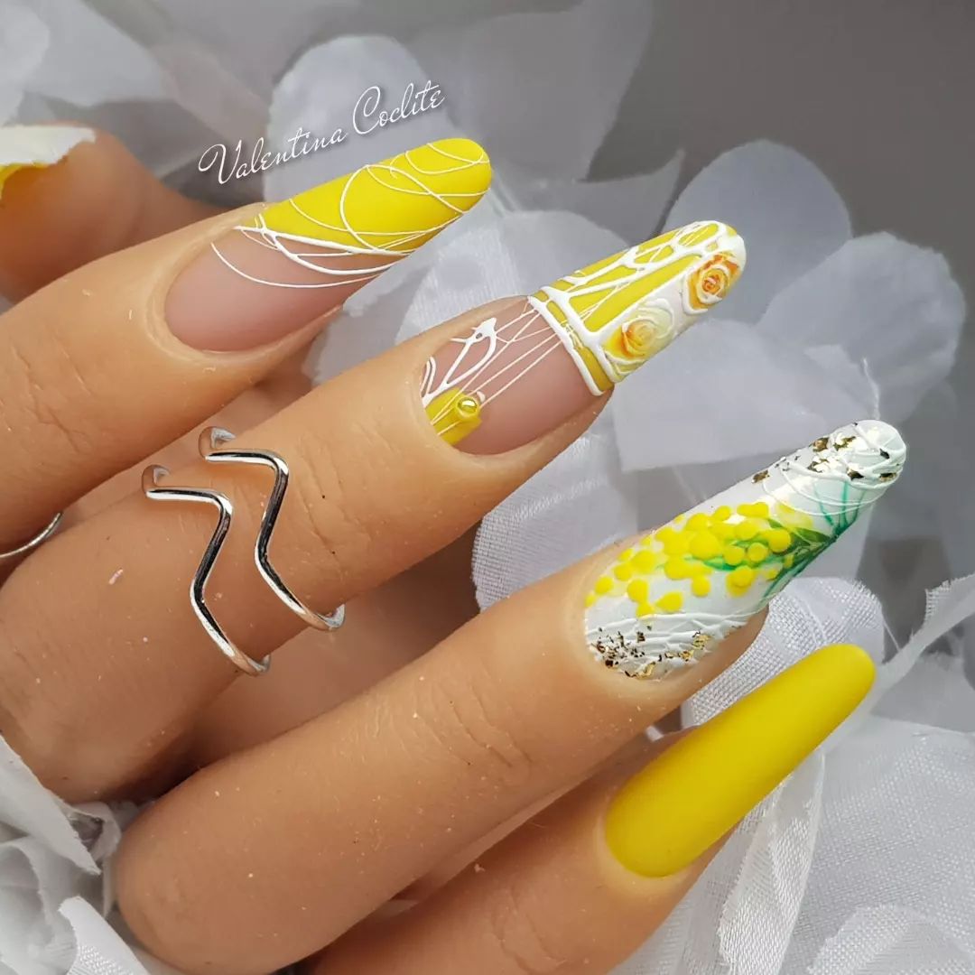 Vernis à ongles jaune et blanc avec des fleurs sur des ongles en amande