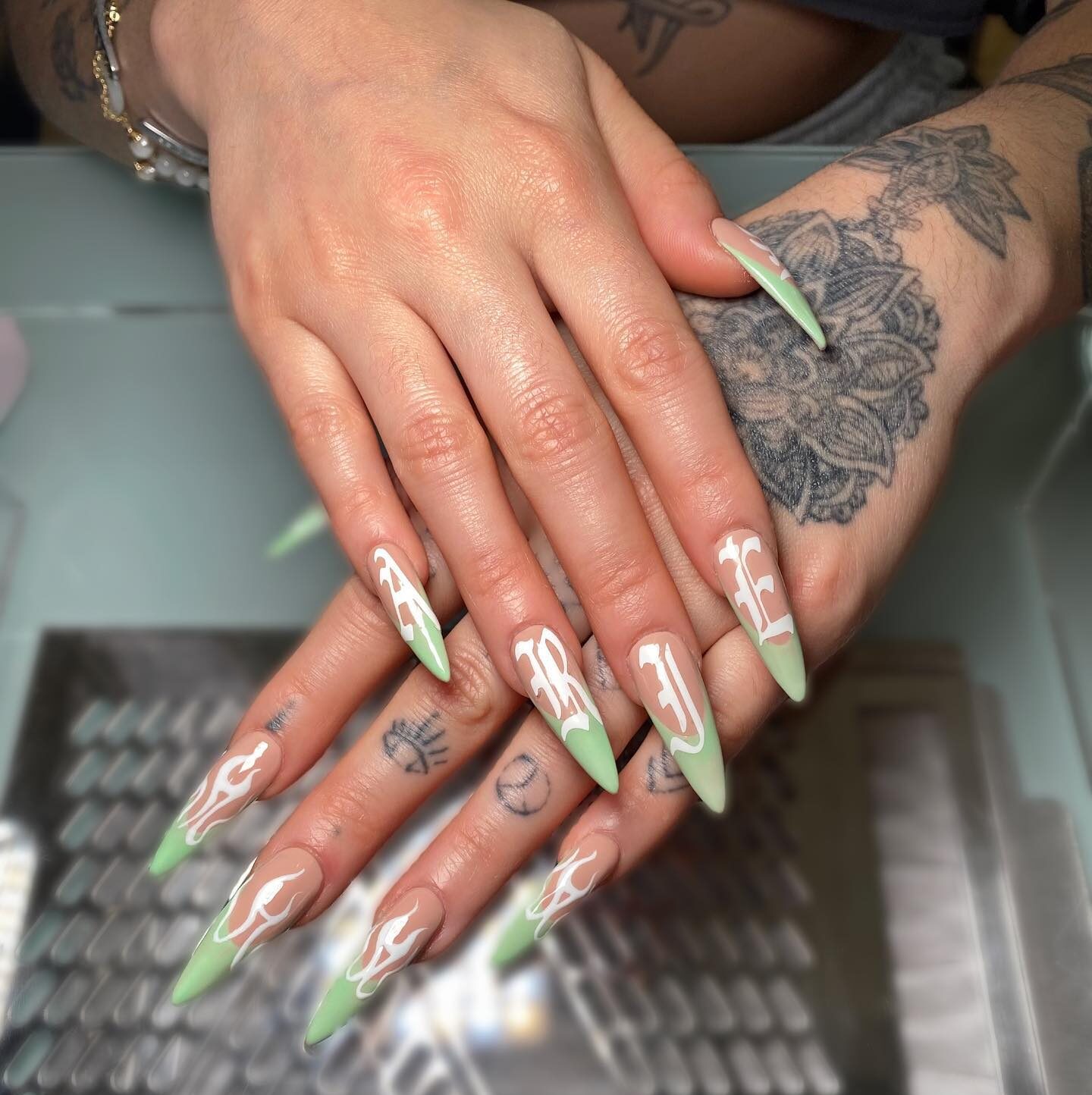 Pointes françaises vert clair avec lettres Bélier et flammes blanches nail arts sur ongles longs à talons aiguilles