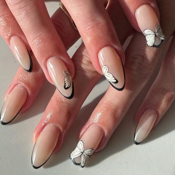 Ongles en acrylique en forme d’amande avec pointes fines françaises noires et nail art papillon blanc