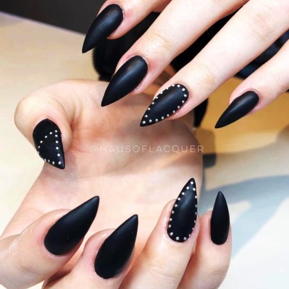 Couleur d’ongle noire au fini mat avec des pois sur de longs ongles aiguilles