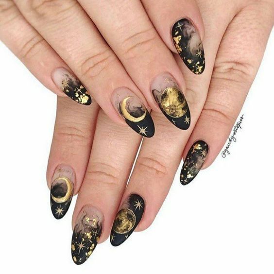 Nail art en marbre fumé noir en finition mate avec des motifs d’ongles célestes dorés sur de longs ongles ronds