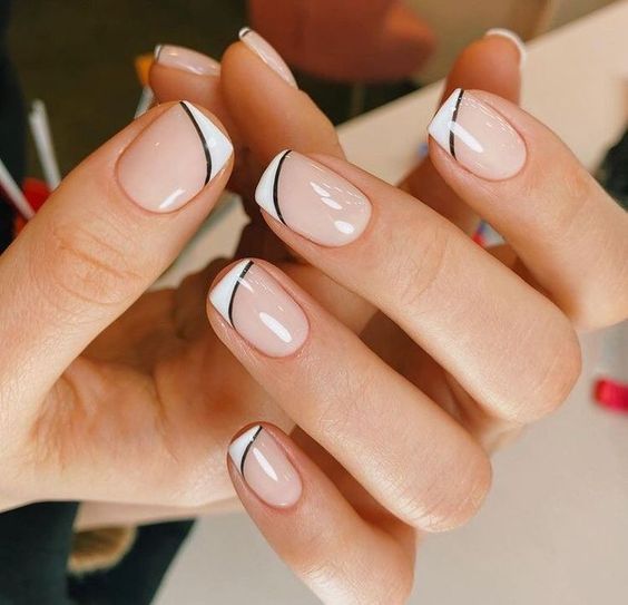 Pointes françaises fines blanches avec des contours noirs sur des ongles carrés courts