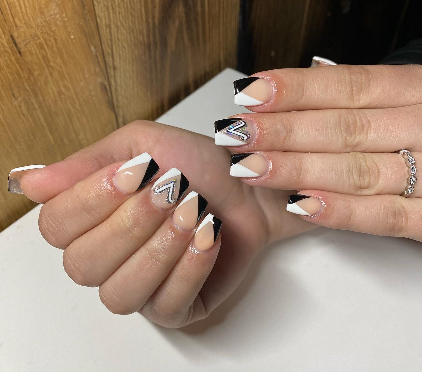 Pointes françaises obliques noires et blanches avec signe Bélier nail art sur ongles carrés moyens de couleur neutre