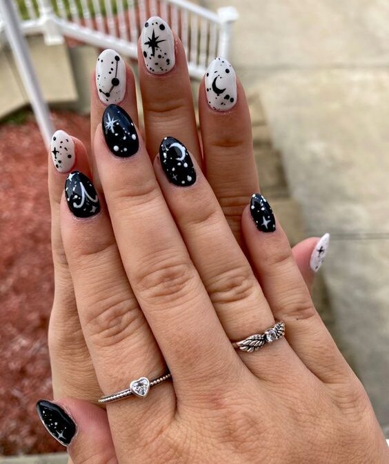 Vernis à ongles noir et blanc avec signe Bélier et éléments célestes motifs d’ongles sur ongles ronds courts