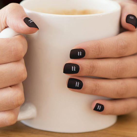 Vernis à ongles noir audacieux au fini mat avec nail art du signe Verseau sur les ongles courts