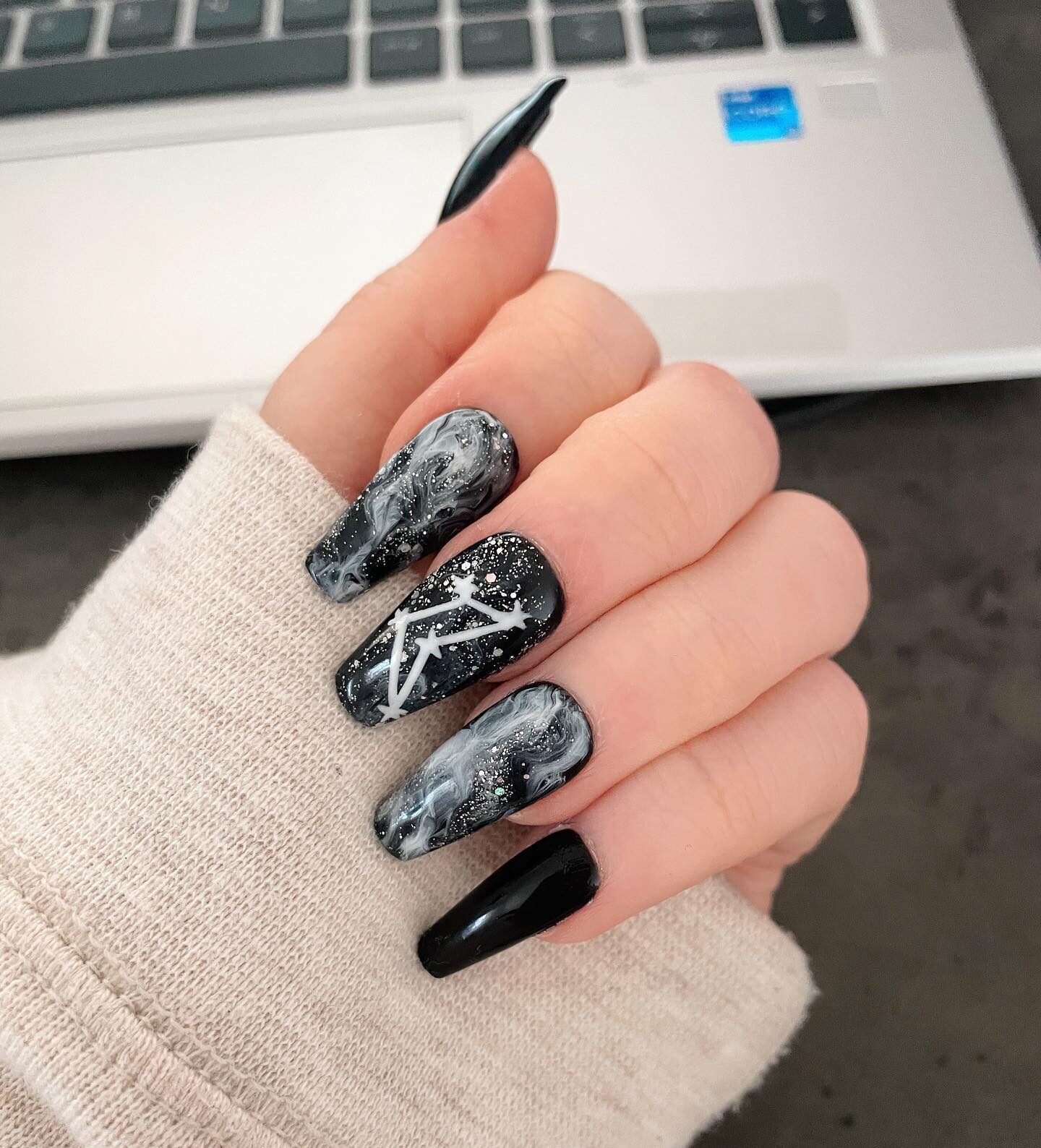 Couleur d’ongle noire avec art d’ongle en marbre fumé et constellation Capricorne sur de longs ongles de cercueil