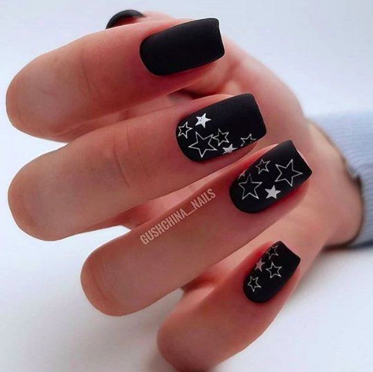 Vernis à ongles noir mat étoiles blanches motifs d’ongles sur ongles carrés effilés moyens