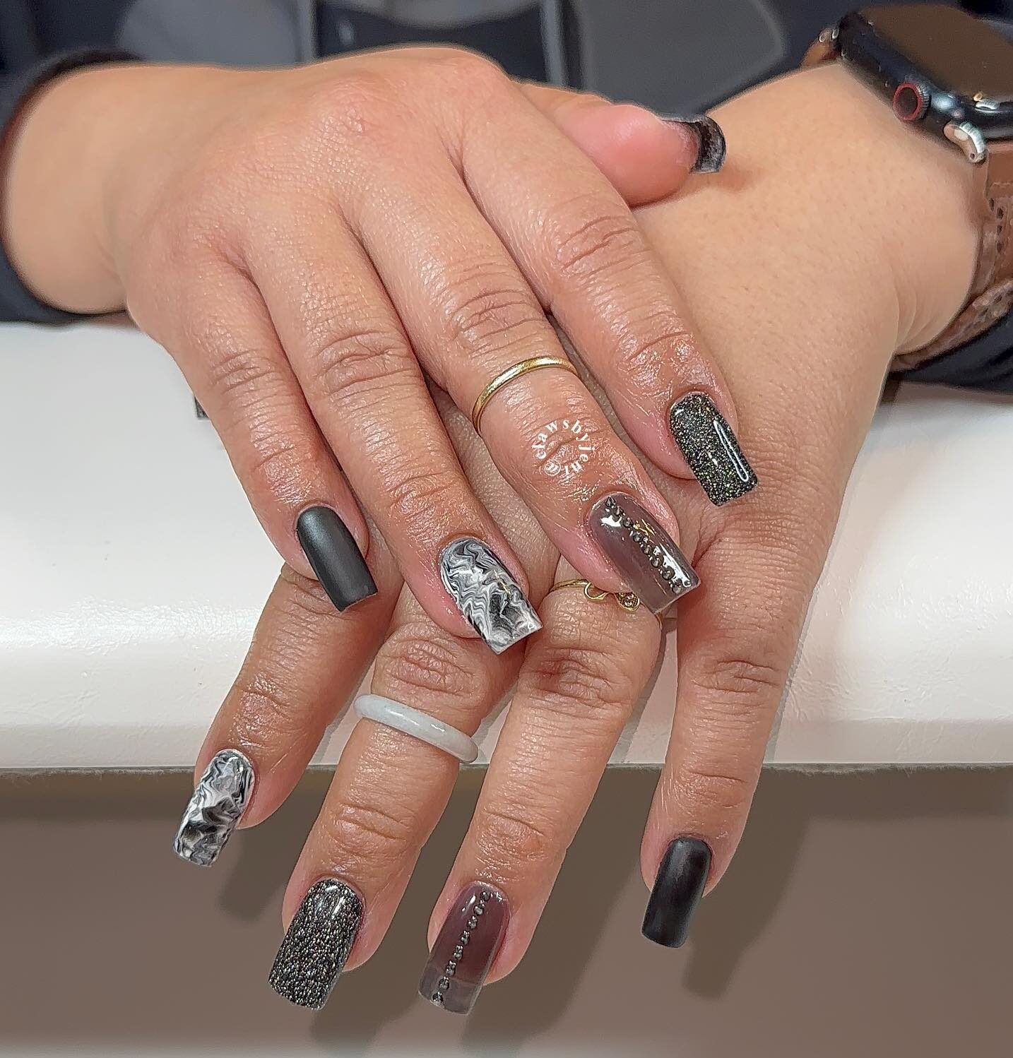 Vernis à ongles de couleur noire et art d’ongle en marbre noir sur ongles en acrylique de forme carrée moyenne