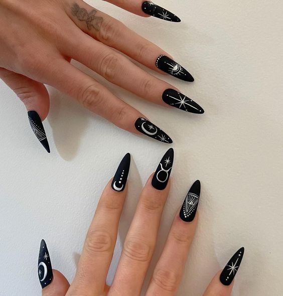 Couleur d’ongles noir profond au fini mat avec signe Taureau blanc et éléments célestes nail arts sur ongles longs à talons aiguilles