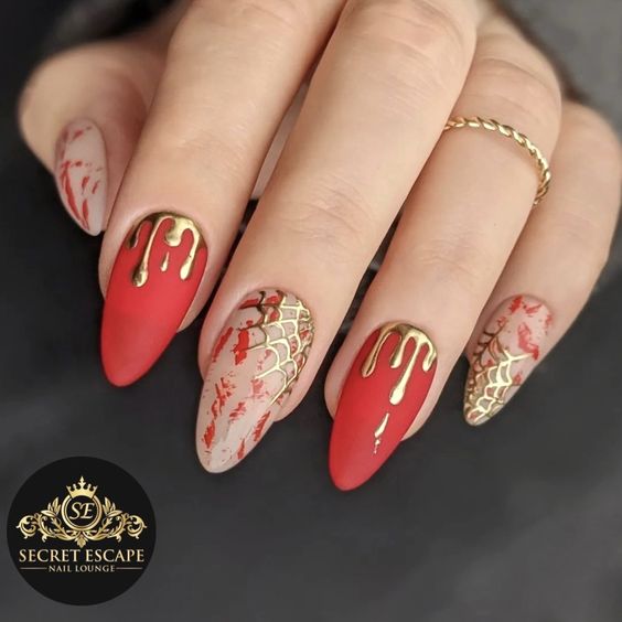 Couleur d’ongle rouge au fini mat avec art d’ongle sang coulant d’or et toiles d’araignée dorées sur de longs ongles en amande