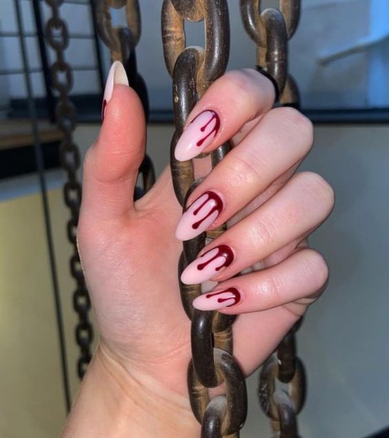 Couleur d’ongle blanc pâle avec un nail art rouge coulant de sang sur de longs ongles en amande