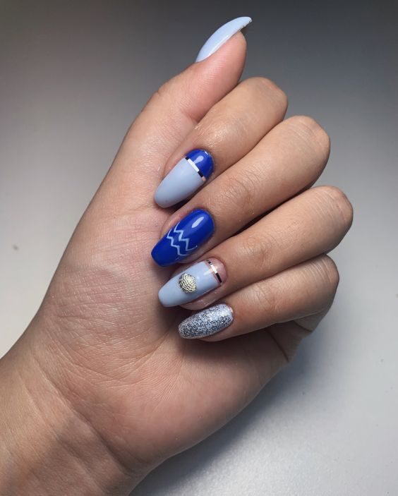 Vernis à ongles bleu foncé et bleu électrique avec des motifs d’ongles d’élément Verseau sur des ongles de cercueil moyens