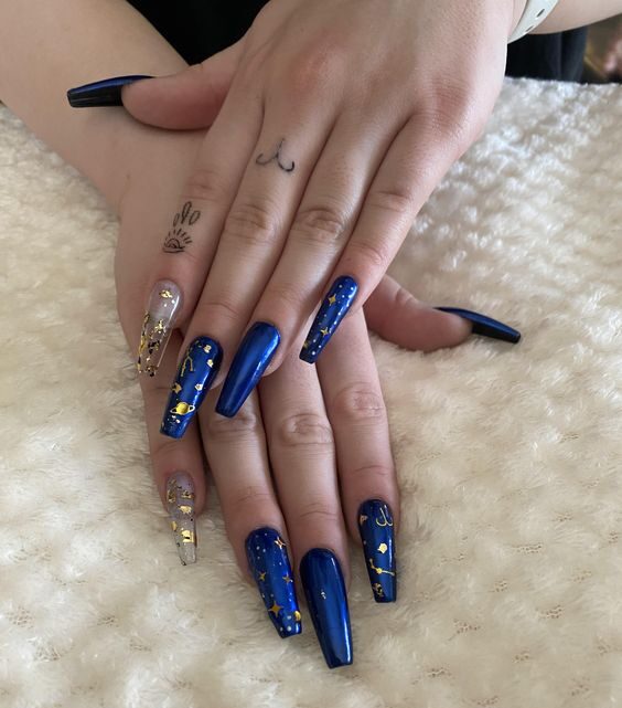 Couleur d’ongle bleu foncé métallique avec signe Bélier doré et éléments célestes nail arts sur de longs ongles en acrylique de cercueil