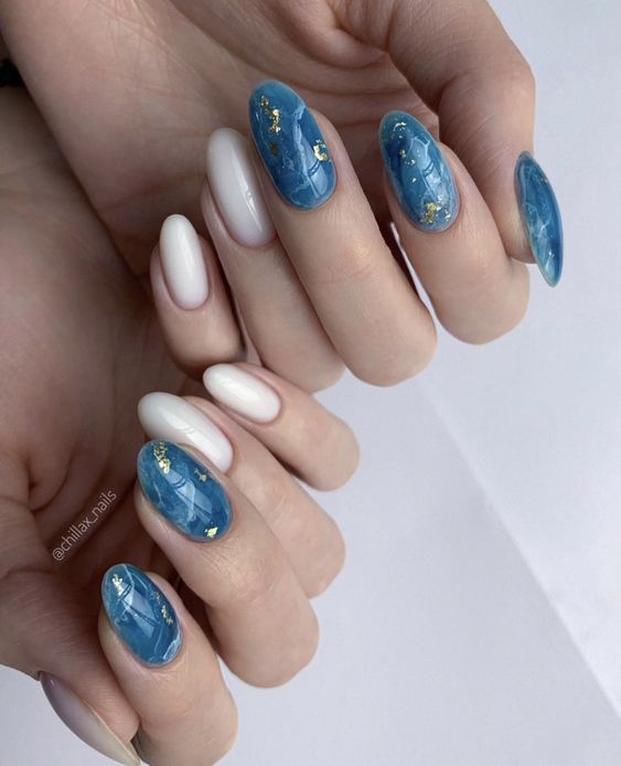 Vernis à ongles blanc et bleu avec des accents de feuille d’or sur les ongles ronds moyens