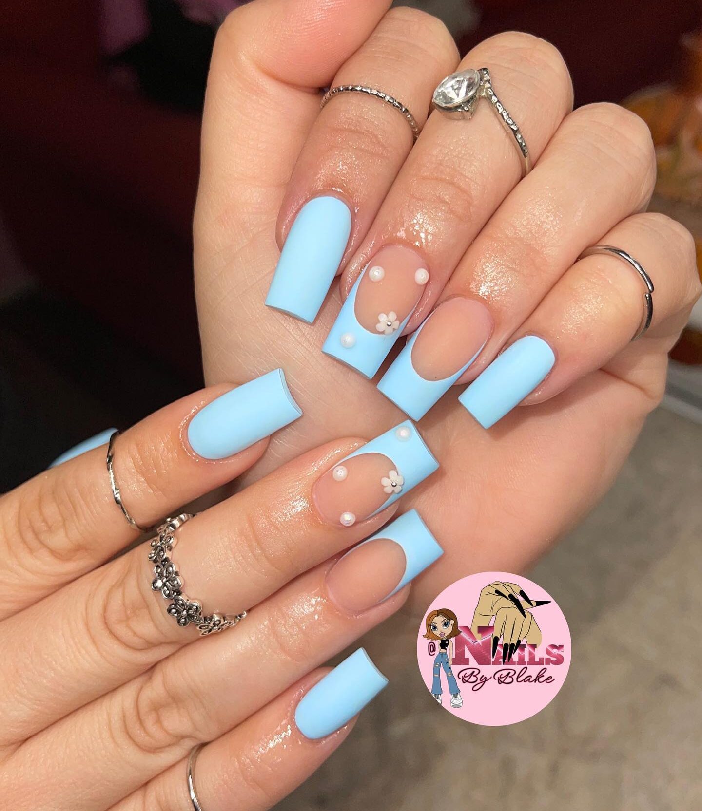 Vernis à ongles bleu clair au fini mat avec des nail arts bling 3D sur des ongles carrés longs et effilés