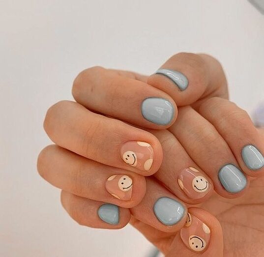 Couleur d’ongle bleu pastel et visages souriants nail art sur ongles courts