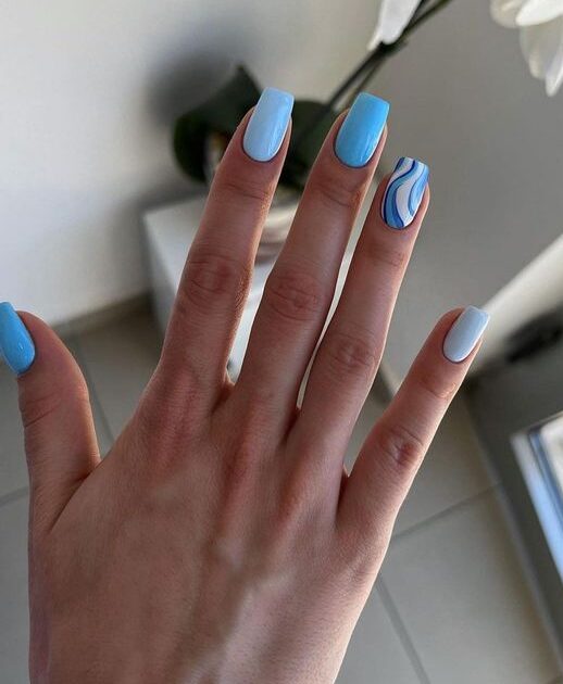 Vernis à ongles bleu clair avec des tourbillons bleus sur les ongles carrés effilés moyens