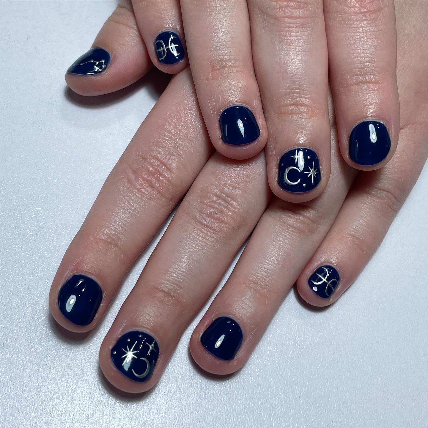 Vernis à ongles bleu foncé avec symbole Poissons et éléments célestes motifs d’ongles sur ongles courts naturels