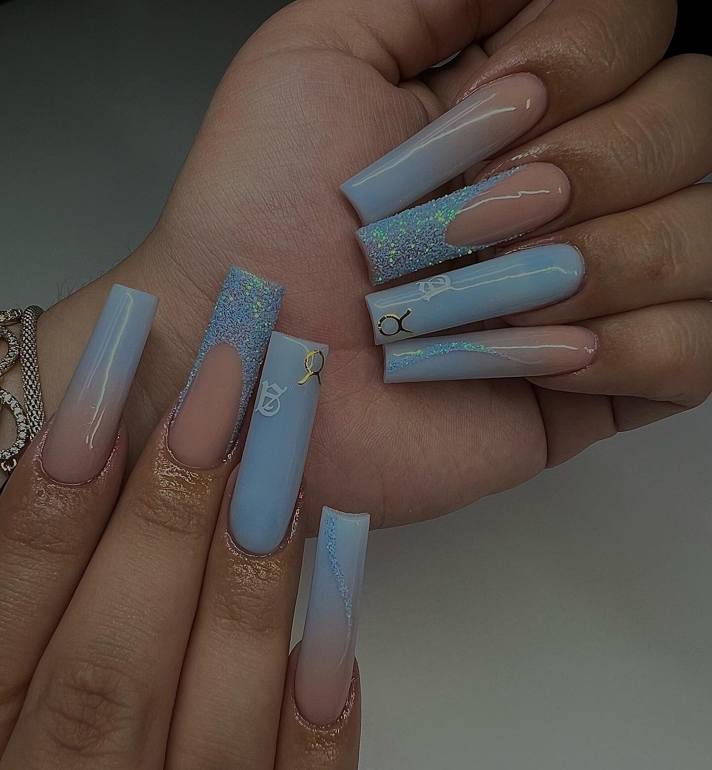 Ombre bleu clair, pointes françaises scintillantes et nail arts du signe Taureau sur des ongles acryliques de forme carrée super longs