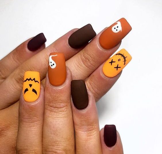 Couleurs d’ongles orange et brun foncé avec des fantômes et des visages effrayants sur des ongles carrés effilés moyens