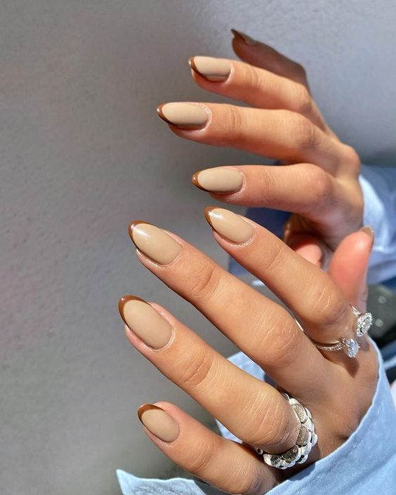 Vernis à ongles de couleur beige avec teinte brune pointes françaises fines sur ongles ronds moyens