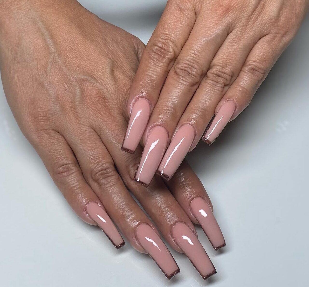 Vernis à ongles couleur nude avec des pointes françaises fines brunes nail art sur des ongles acryliques de forme carrée super longue