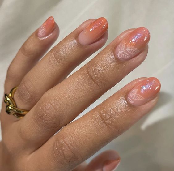 Conception d’ongles ombrée orange brunâtre pâle avec des paillettes et des feuilles nail art sur des ongles ronds moyens