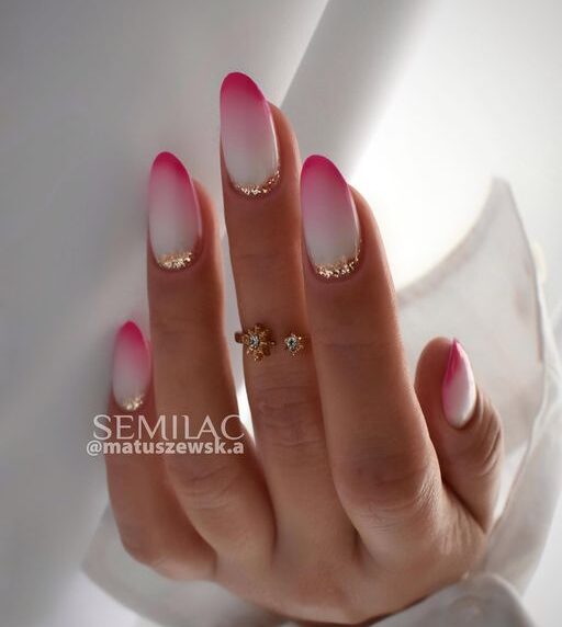 Nail art chic à effet ombré rose et blanc avec des accents dorés sur des ongles ronds moyens