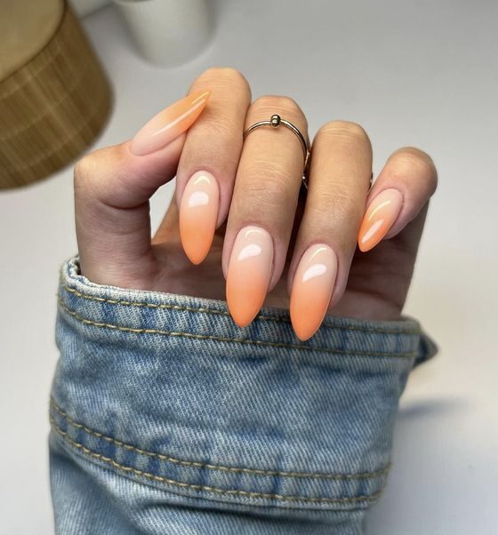 Design ombré crémeux nude et orange sur de longs ongles en amande