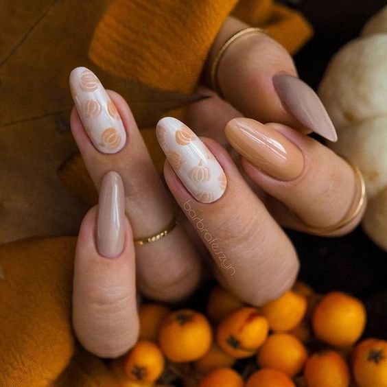 Nuances de couleur d’ongle marron avec des motifs d’ongles de citrouille sur de longs ongles ronds