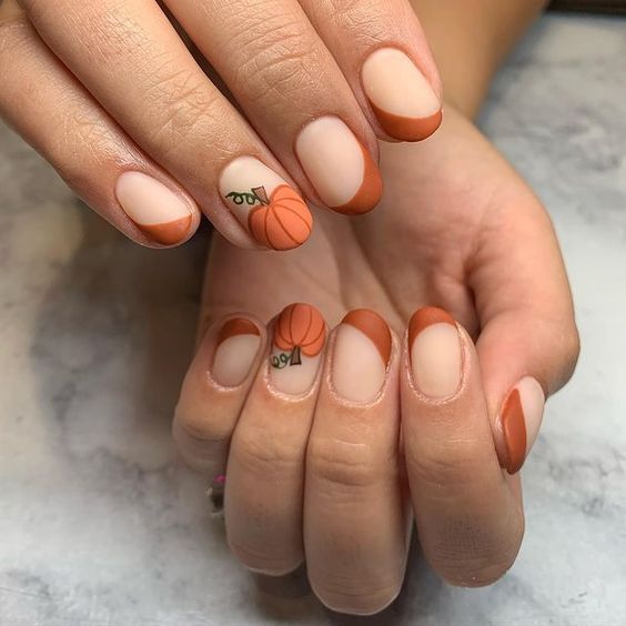 Ongles courts ronds en acrylique avec finition mate, pointes françaises orange brûlé et motifs d’ongles en forme de citrouille