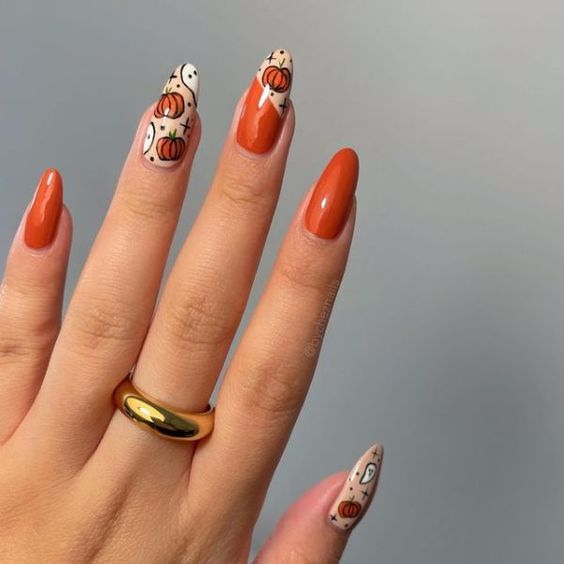 Couleur des ongles orange brûlé avec des ongles en forme de citrouille sur les ongles ronds moyens