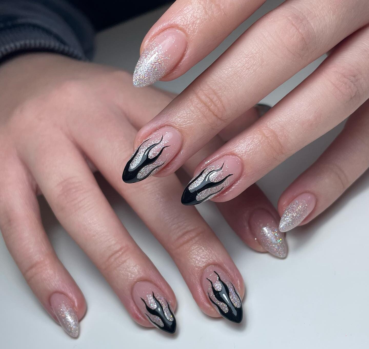 Embouts français de couleur argentée avec motif de flamme noire sur les ongles longs en amande 