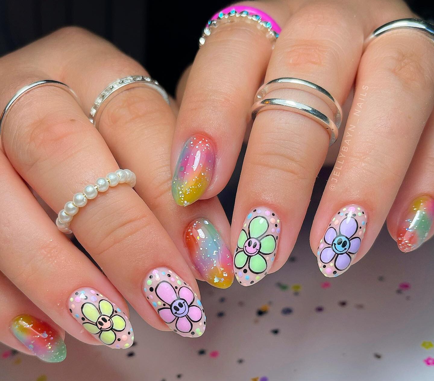 Nail art ombré coloré et fleurs multicolores avec des smileys sur des ongles courts en amande