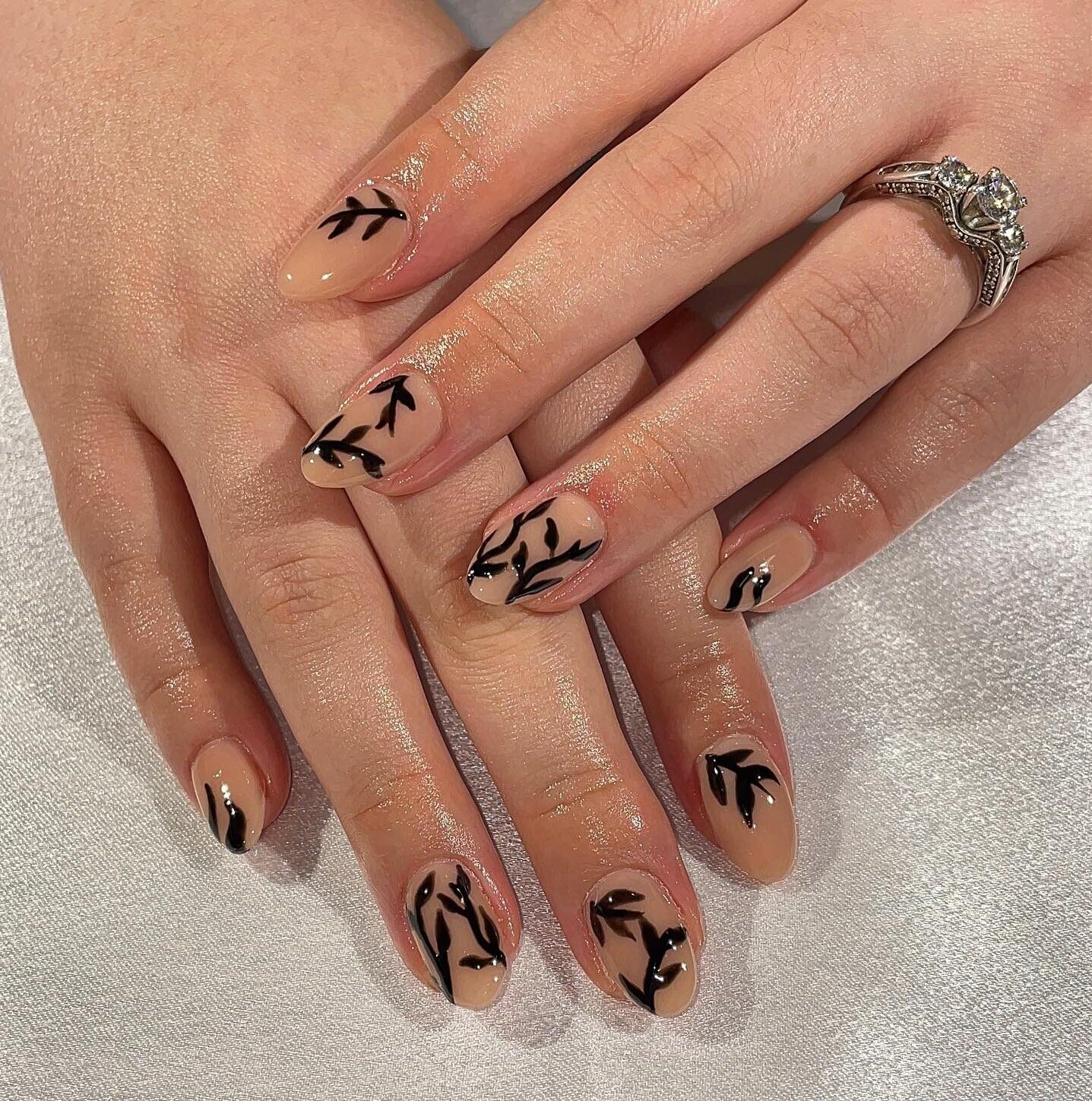 Vernis à ongles nude avec des nail arts printaniers noirs sur ongles ronds moyens