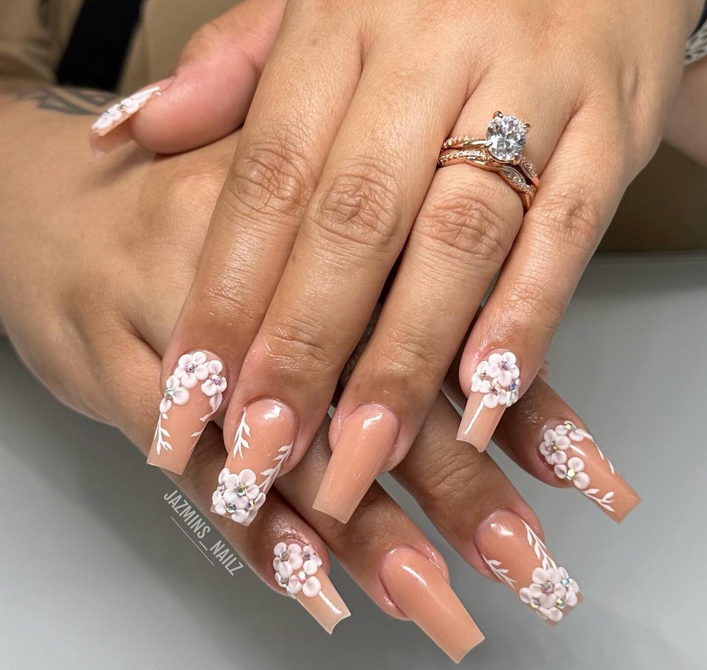 Vernis à ongles de couleur neutre avec des motifs d’ongles de fleurs 3D sur de longs ongles carrés effilés