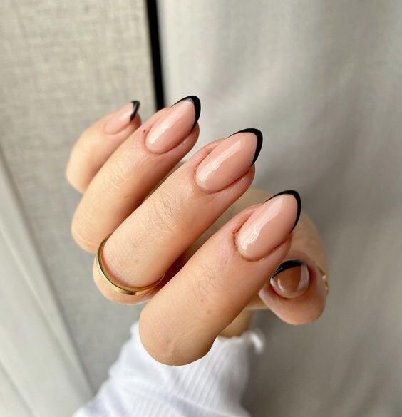 Couleur d’ongle nude avec des pointes françaises fines noires sur des ongles ronds moyens