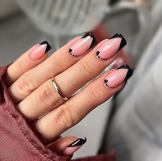 Vernis à ongles nude avec des petits cœurs nail art et pointes françaises noires sur ongles carrés moyens