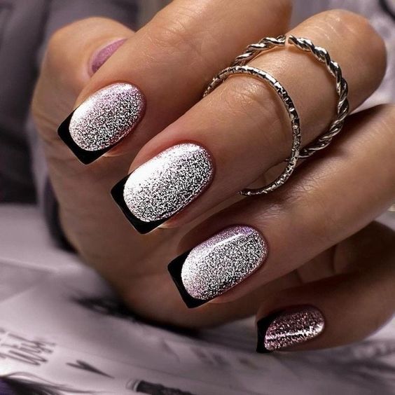 Vernis à ongles argenté scintillant avec des pointes françaises noires sur des ongles courts et carrés