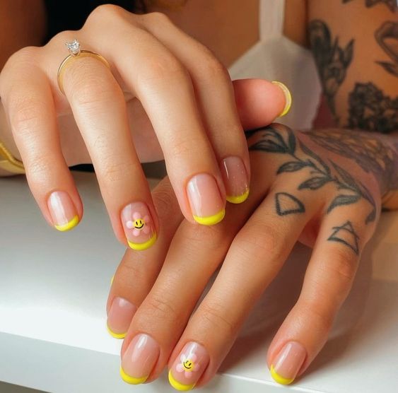 Ongles courts naturels avec pointes jaunes Français et nail art smiley face