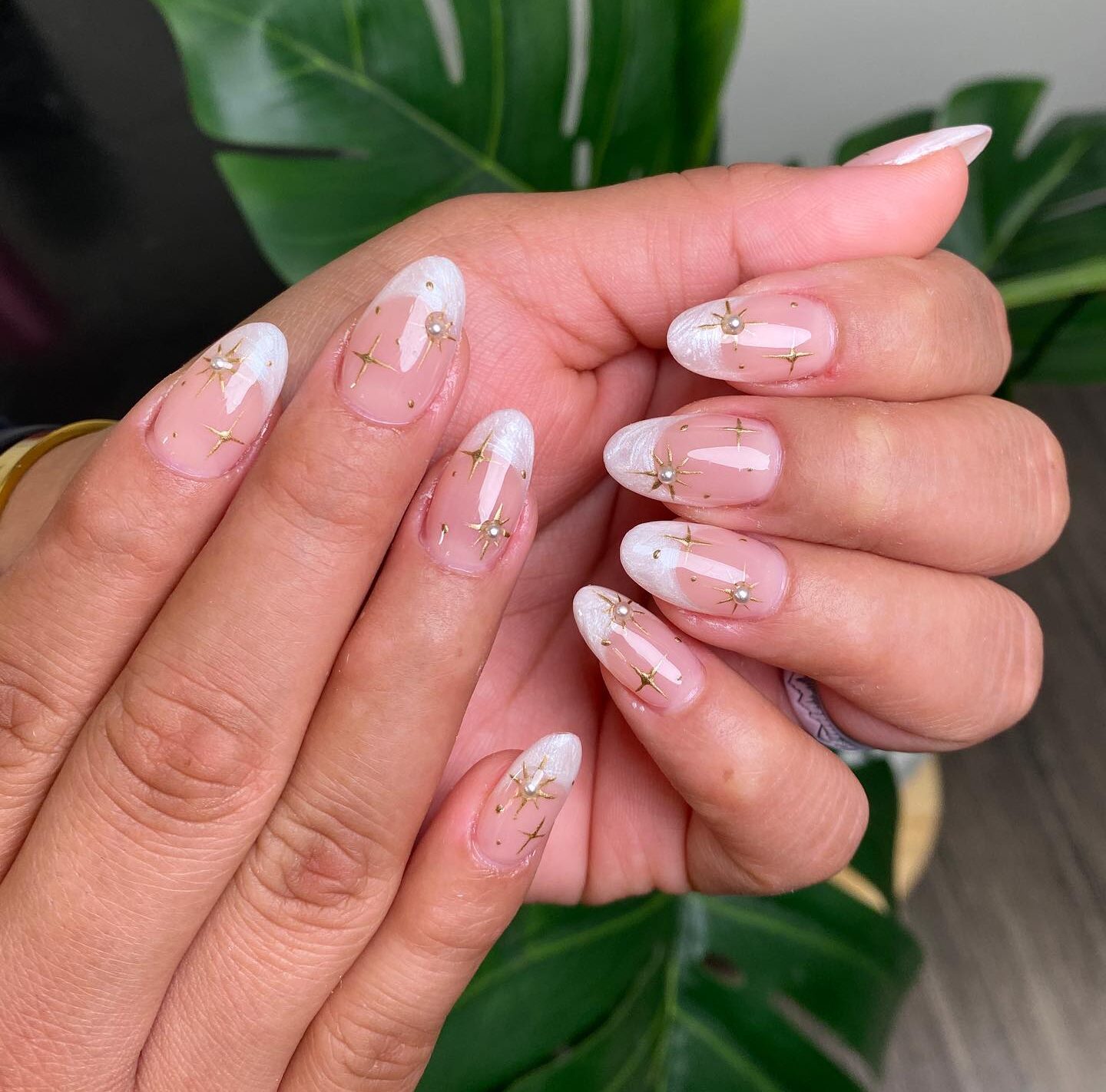 Ongles ronds moyens clairs avec des pointes françaises blanc nacré et des nail arts d’éléments célestes