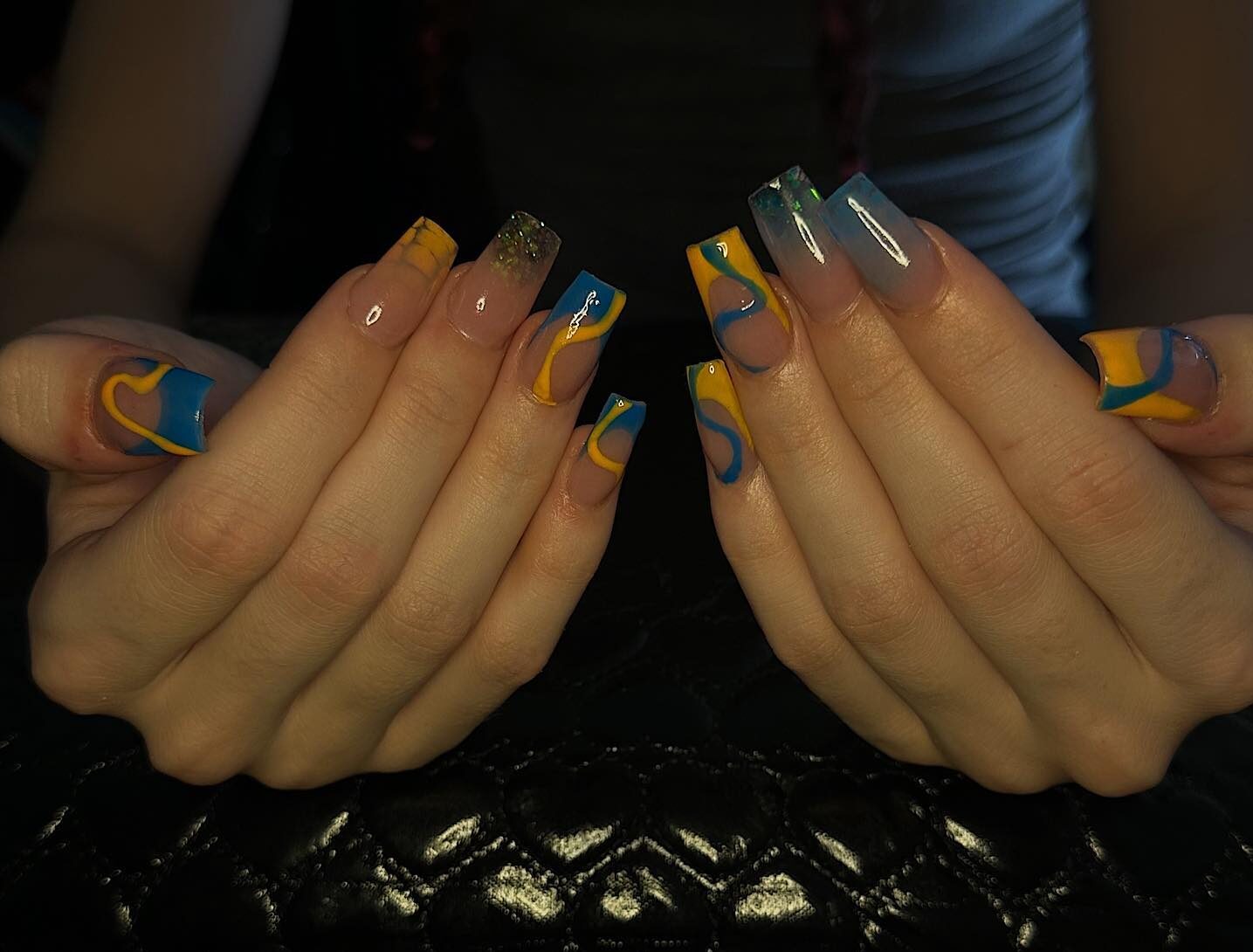 Tourbillons bleus et jaunes et pointes françaises sur de longs ongles carrés effilés en acrylique